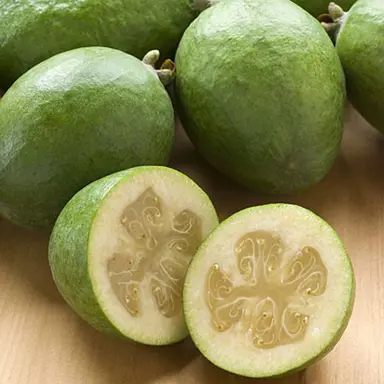 Feijoa Takaka fruit on a table with one cut in half.
