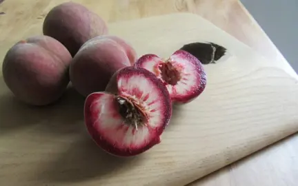 'Sanguine' Peaches cut in half on a table.