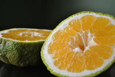Ugli fruit cut in half revelaing orange flesh.